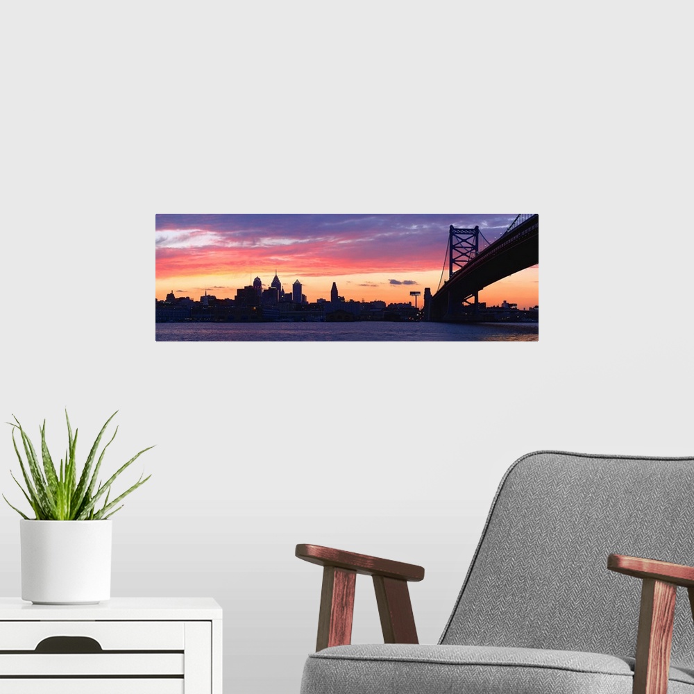 A modern room featuring View from the shoreline under the bridge of pastel-colored clouds over the city skyline at dusk.