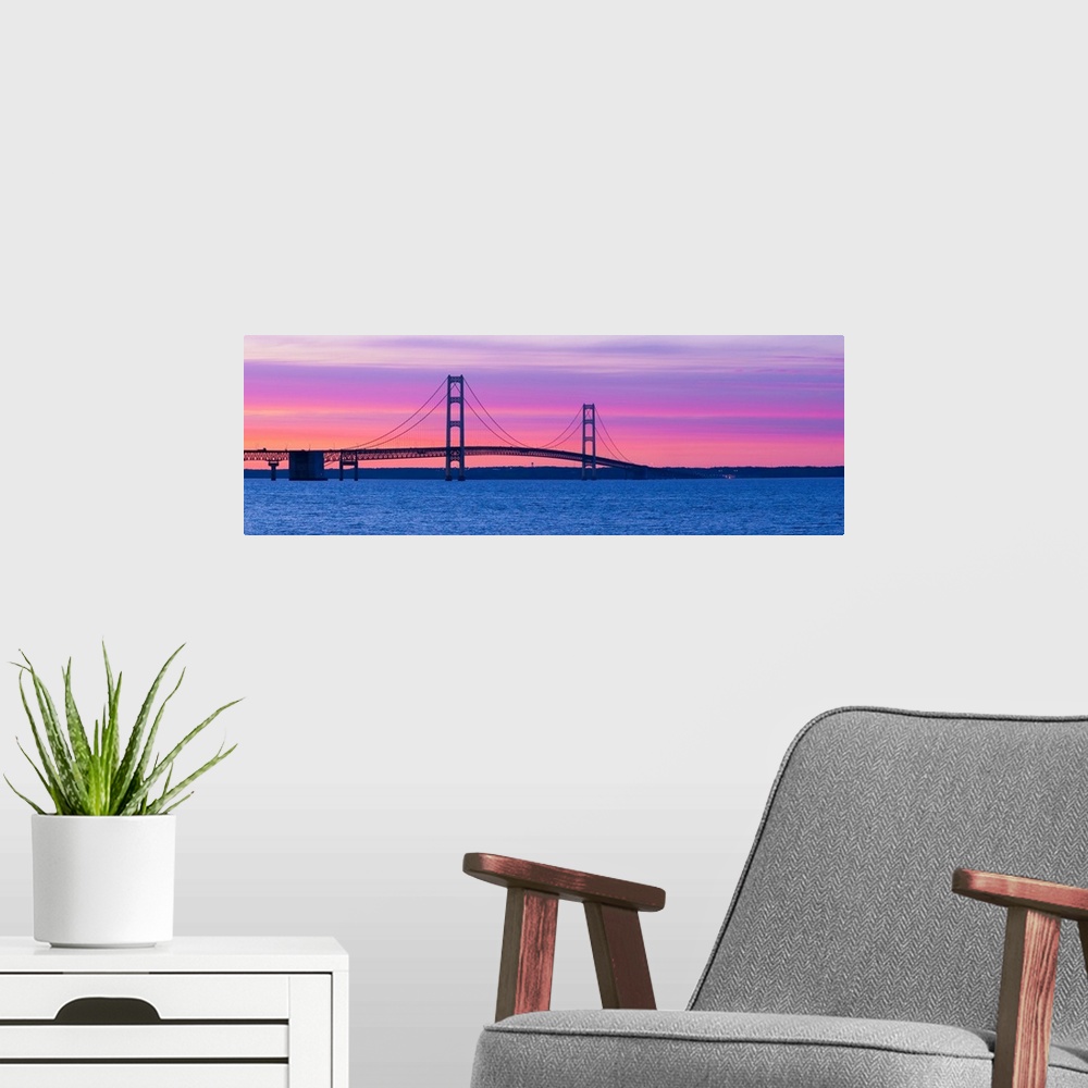 A modern room featuring Panoramic photograph shows a long overpass spanning a large body of water and connecting two port...