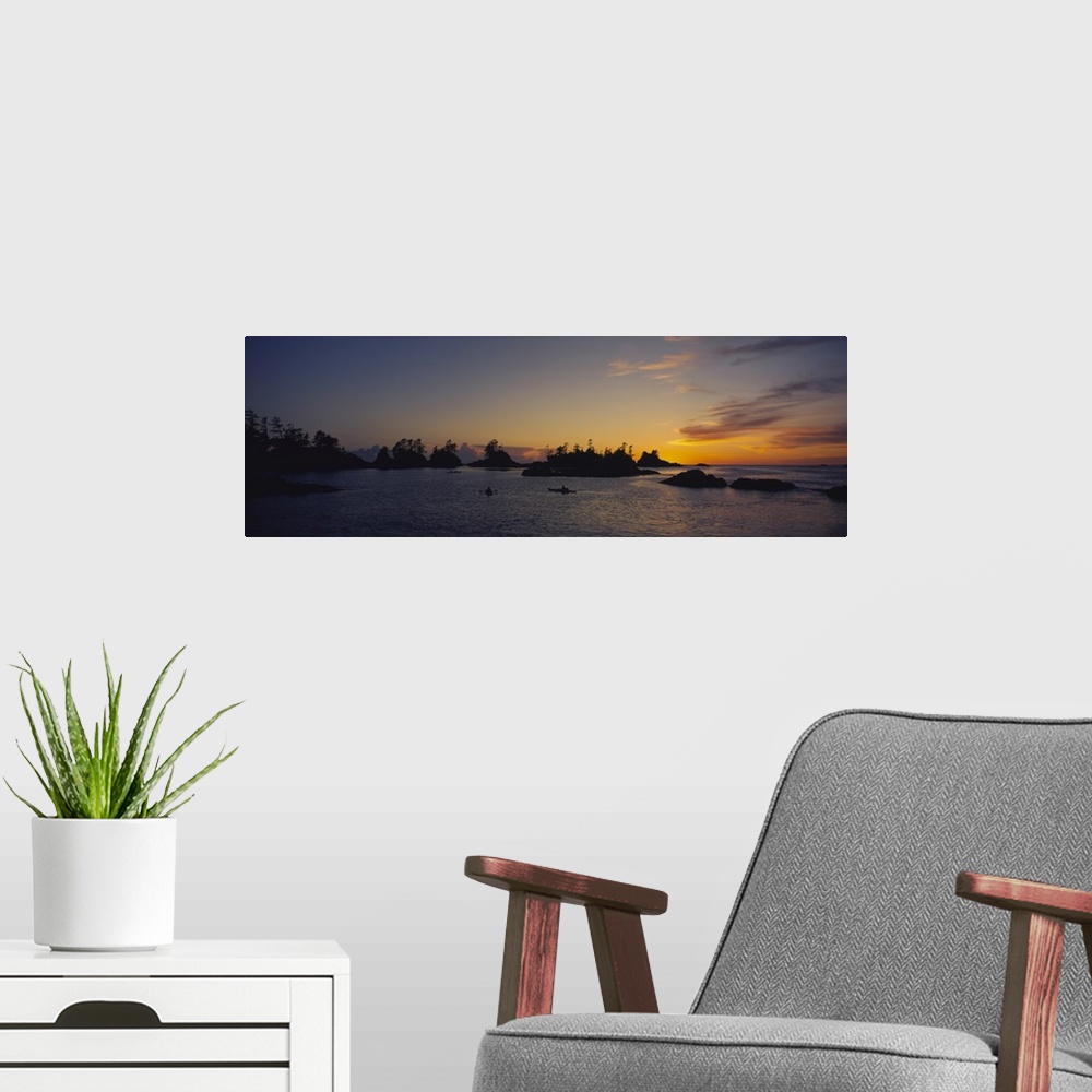 A modern room featuring Tiny islands and boats on the water are silhouetted by the sunset that has gone below the horizon.