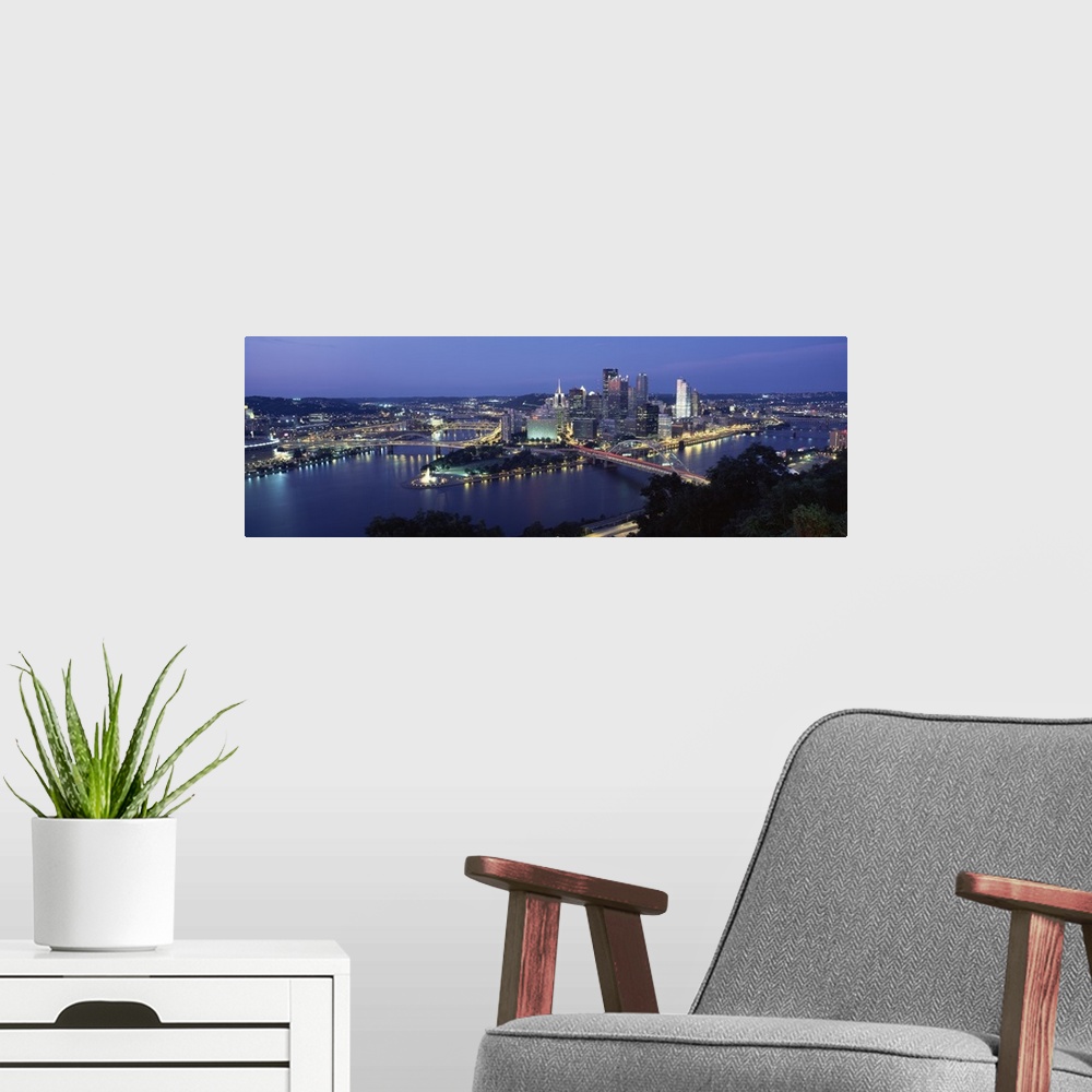 A modern room featuring Large panoramic photo of downtown Pittsburgh, Pennsylvania (PA) lit up at night. Multiple bridges...
