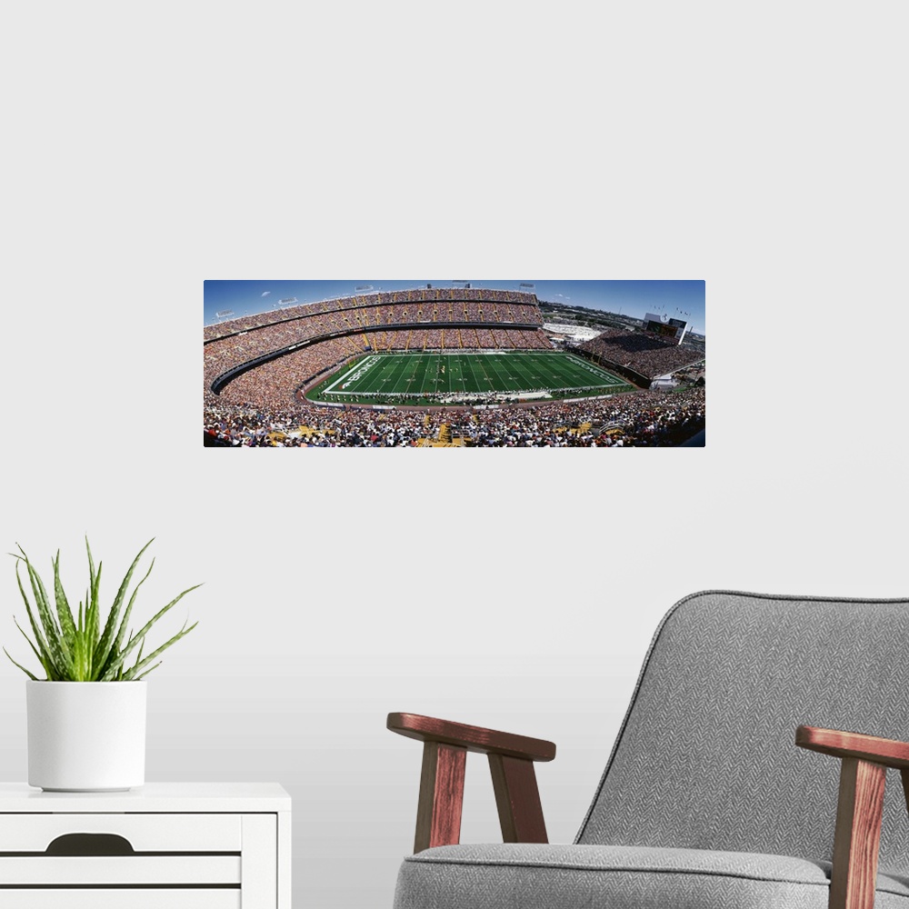 A modern room featuring A wide angle shot of a full Broncos stadium on a bright, sunny day.