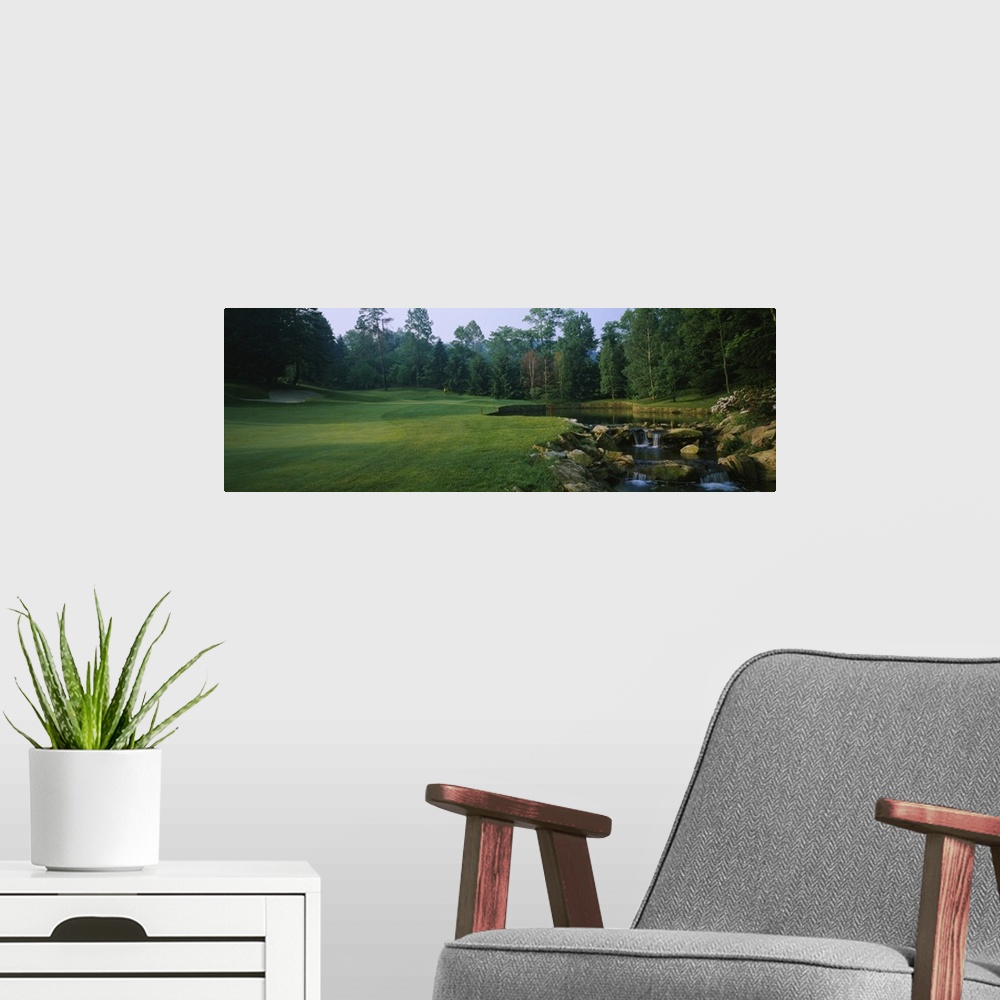 A modern room featuring This is a panoramic photograph of a landscaped lawn and trees next to a small cultivated stream.