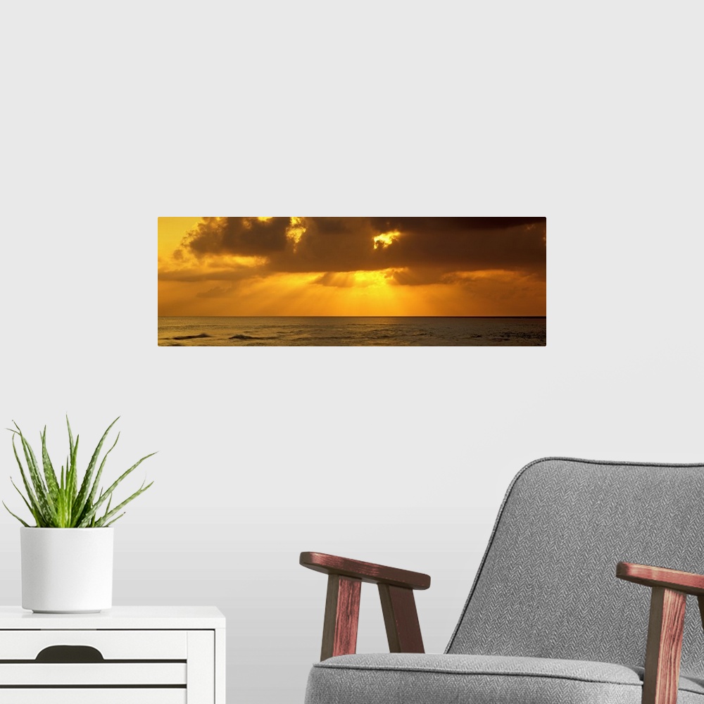 A modern room featuring Sunbeams radiating through clouds over the ocean