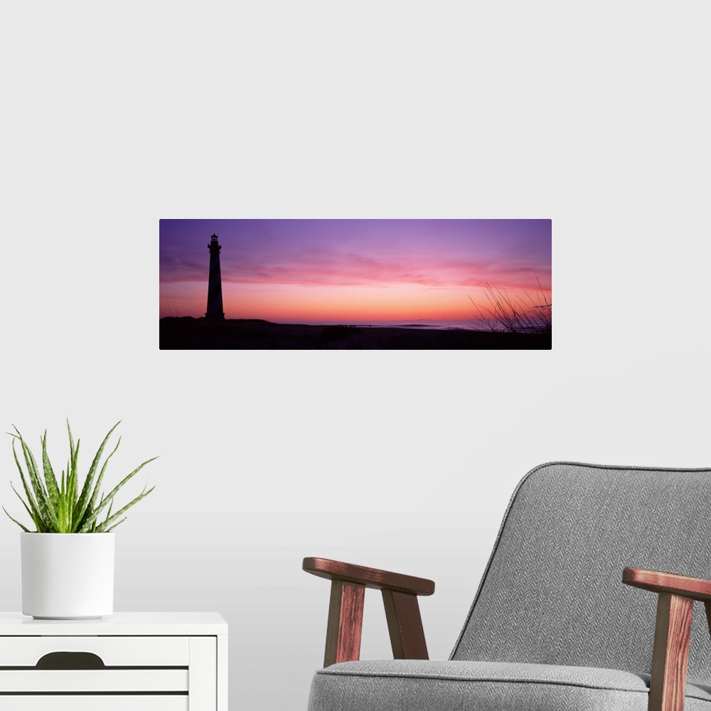 A modern room featuring A panoramic canvas with a pastel colored sky with a light house towering over the sandy beach on ...