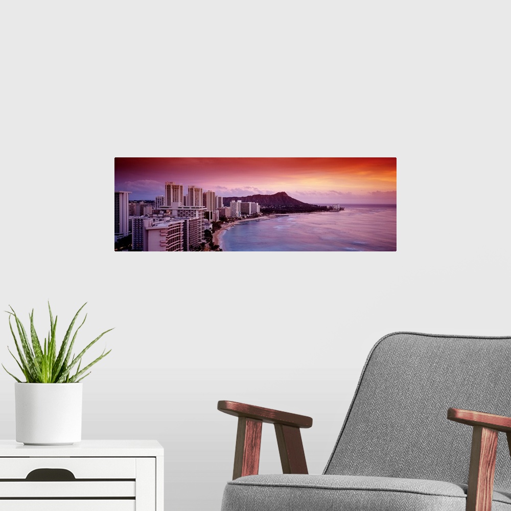 A modern room featuring Rosy colors from the setting sun wash over the tropical island city next to the waterfront on Wai...