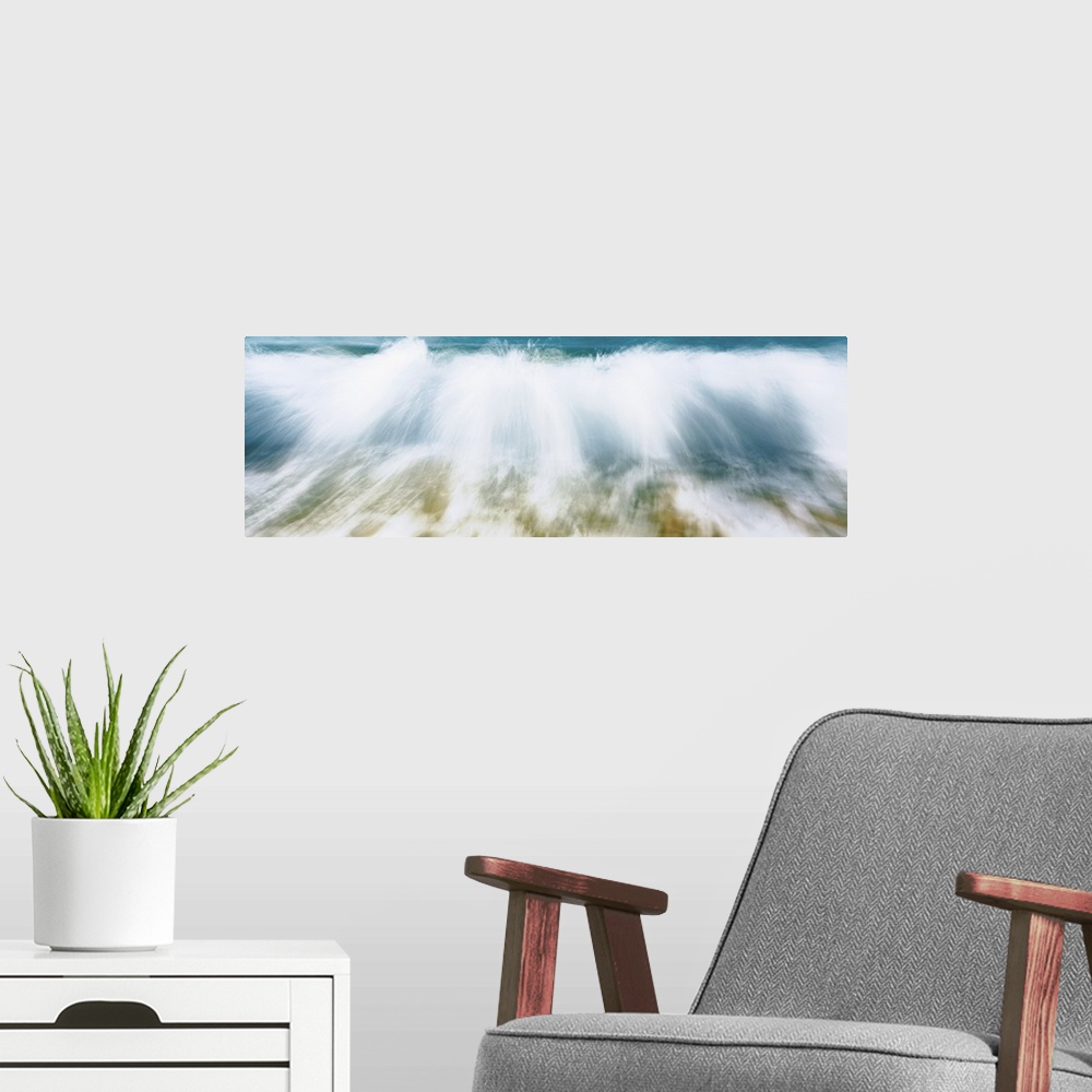 A modern room featuring Up-close panoramic photograph of wave crashing onto beach creating spray.