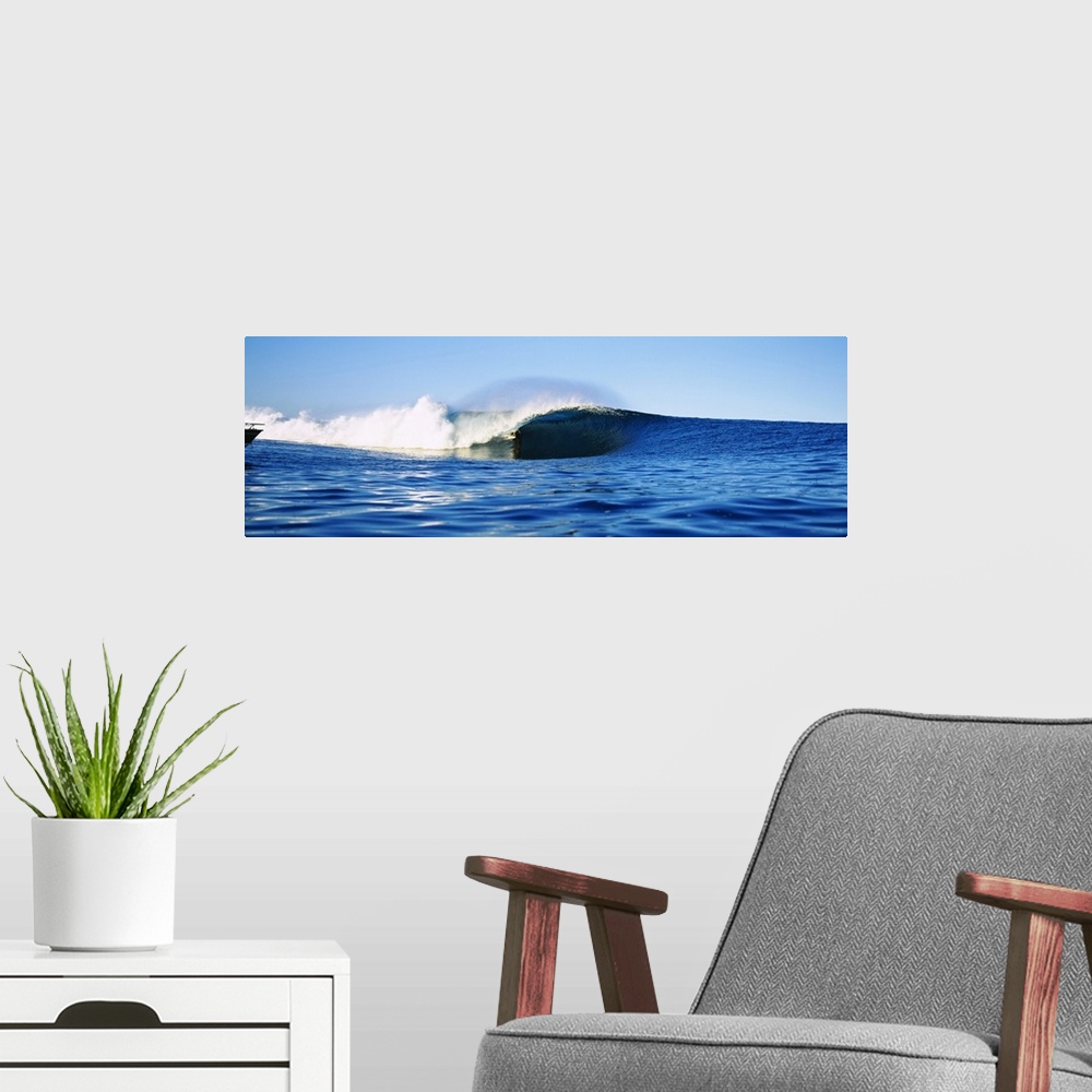A modern room featuring Large, horizontal photograph of a distant surfer riding a large wave, in the blue waters of Tahit...