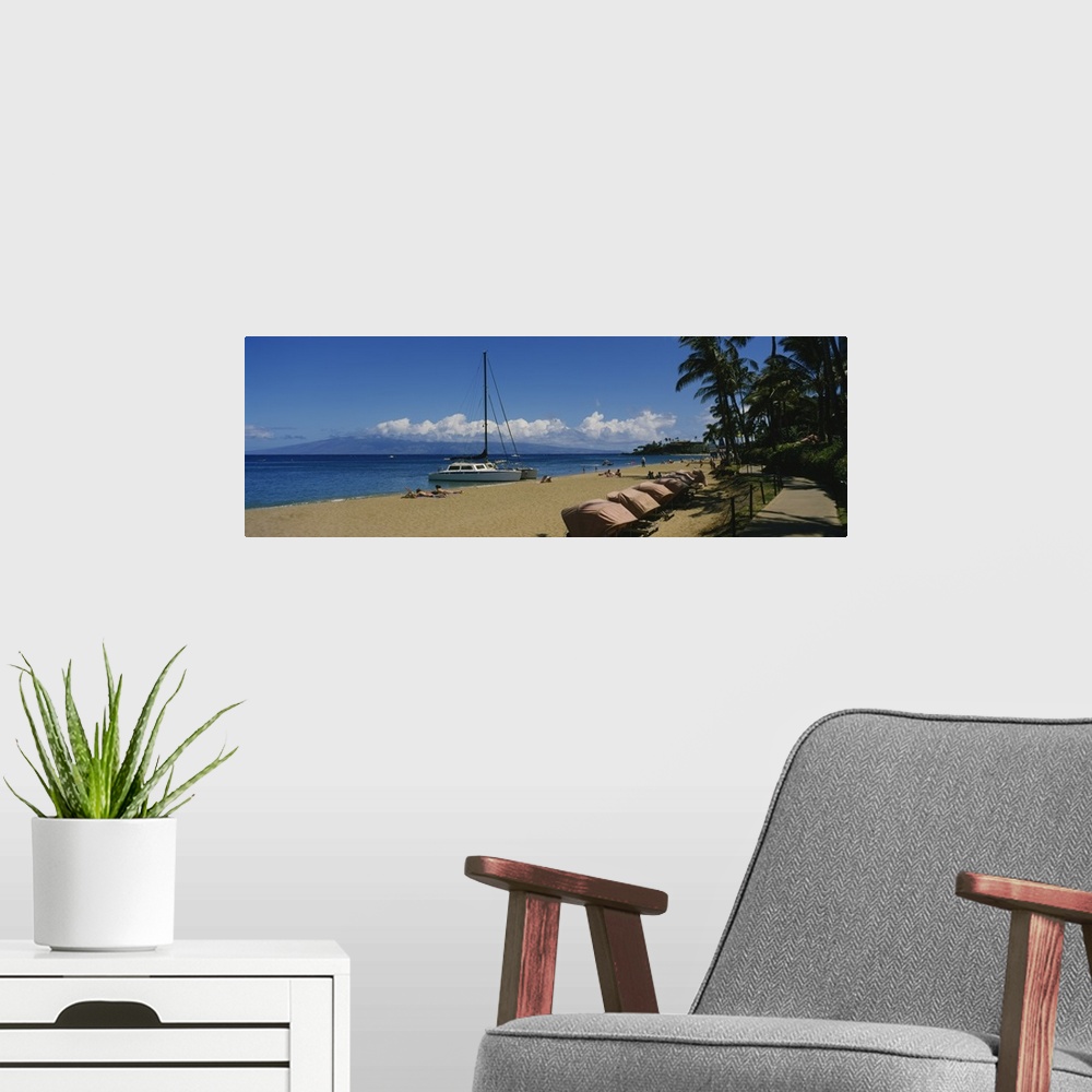 A modern room featuring Panoramic photograph of shoreline filled with beachgoers and docked sailboats under a cloudy sky.