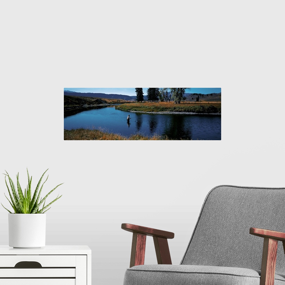 A modern room featuring Giant, landscape photograph of Slough Creek in Yellowstone National Park in Wyoming, surrounded b...
