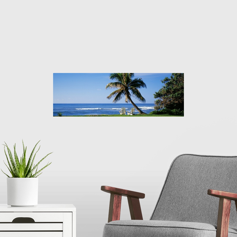 A modern room featuring This is a panoramic photograph of a grassy lawn that grows up the shoreline where two lounge chai...