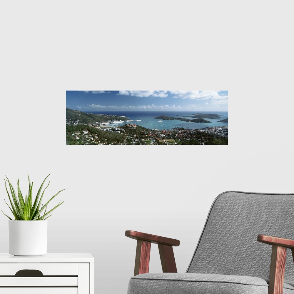 A modern room featuring Panoramic photograph of aerial view of city near water's edge under a cloudy sky.