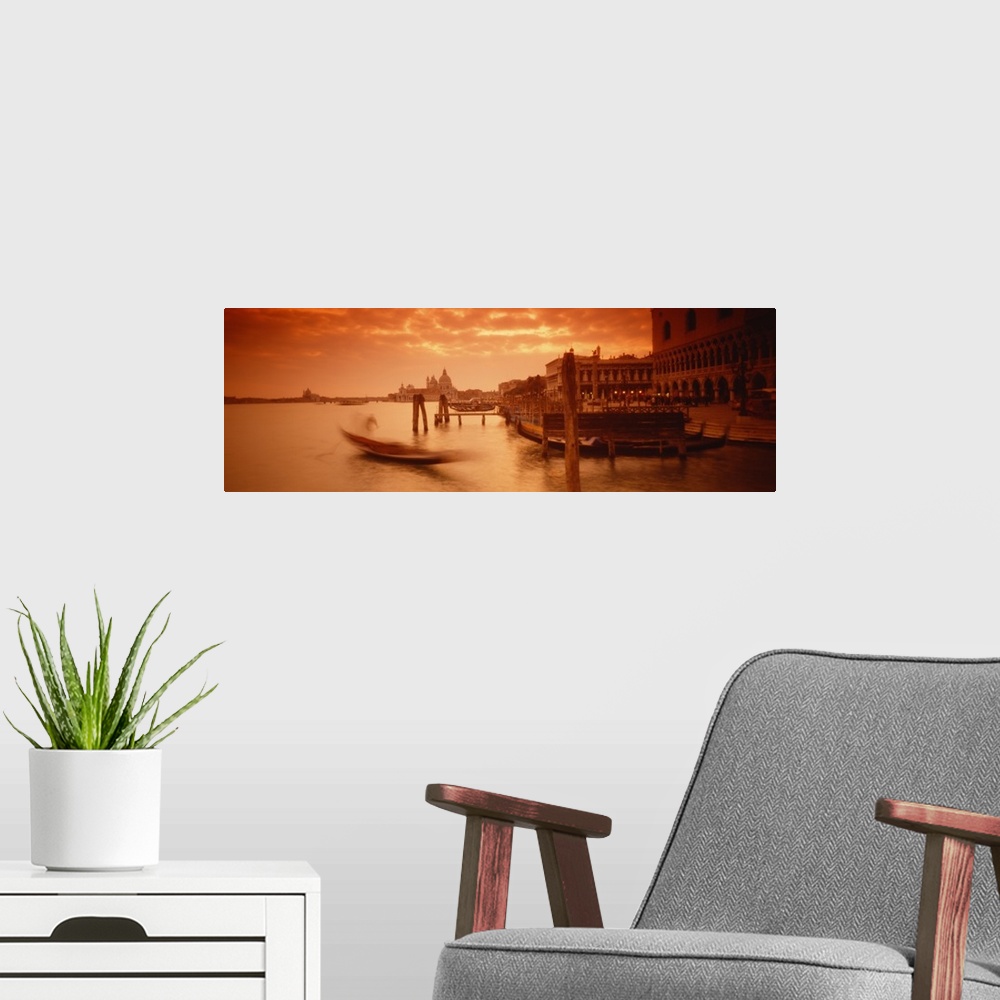 A modern room featuring Panorama of a small Italian harbor with a blurred gondola coming into port at sunset.