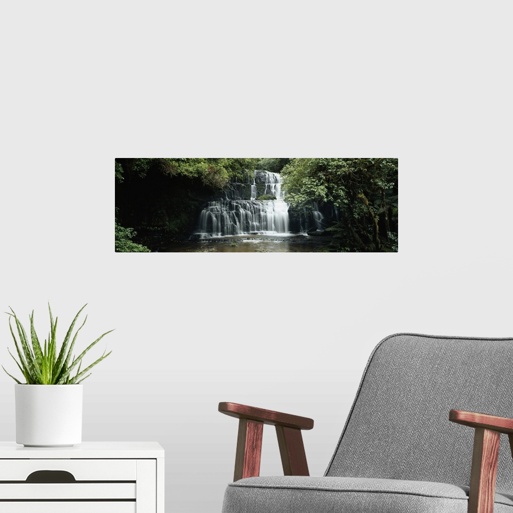 A modern room featuring Wide angle photograph of green trees and foliage surrounding Purakaunui Falls in the Catlins, on ...