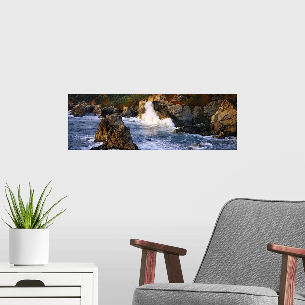A modern room featuring Horizontal photo print of waves crashing into rocky cliffs in the Pacific Ocean and rock formatio...