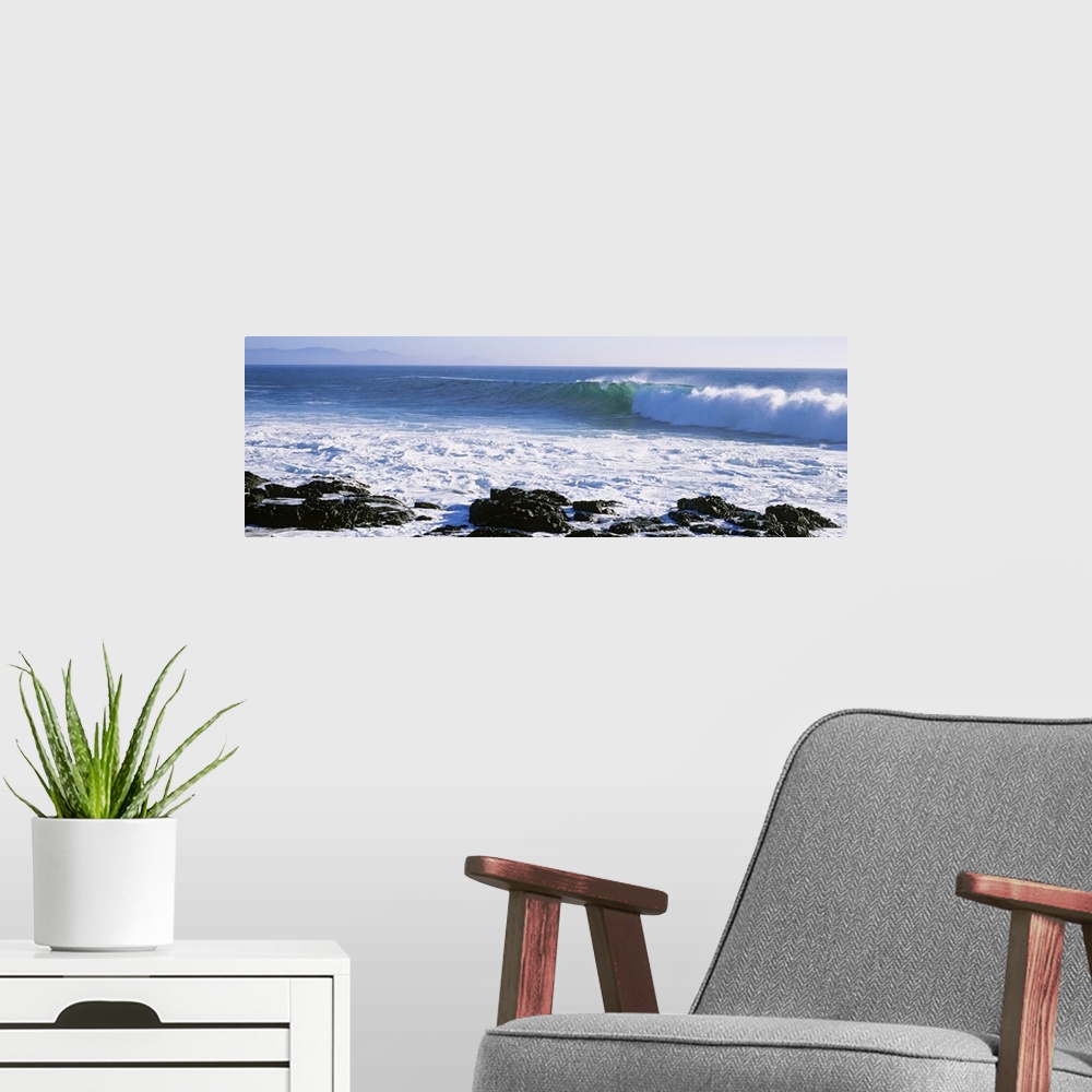 A modern room featuring Long image on canvas of big waves crashing onto a rocky shore.