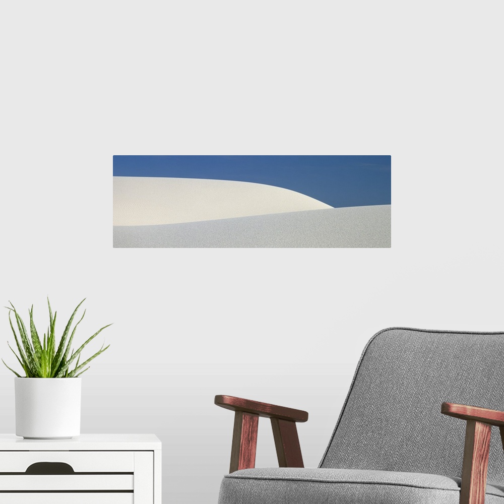 A modern room featuring Panoramic photograph of the sloping dunes of White Sands, New Mexico, contrasting with the darker...