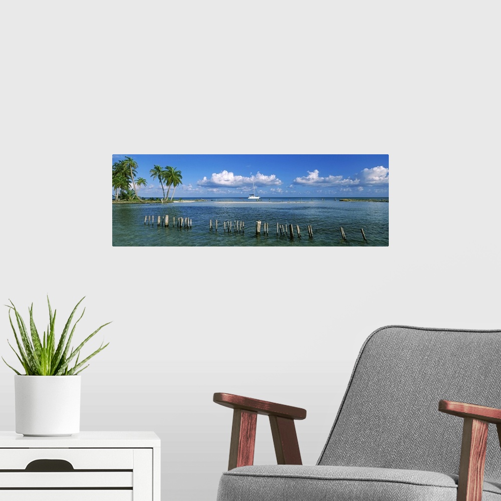 A modern room featuring Wooden posts in the sea with a boat in background, Laughing Bird Caye, Victoria Channel, Belize