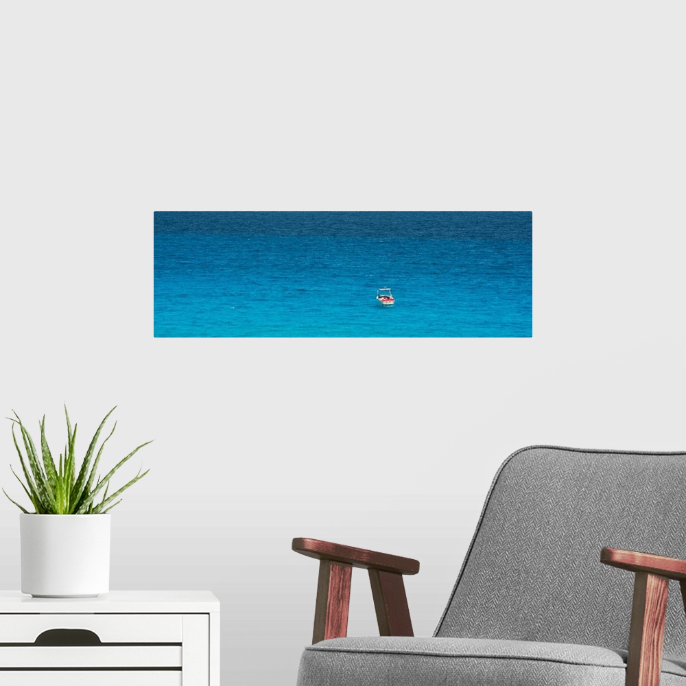 A modern room featuring Panoramic photograph of a single boat floating in the bright blue ocean. From the Viva Mexico Pan...