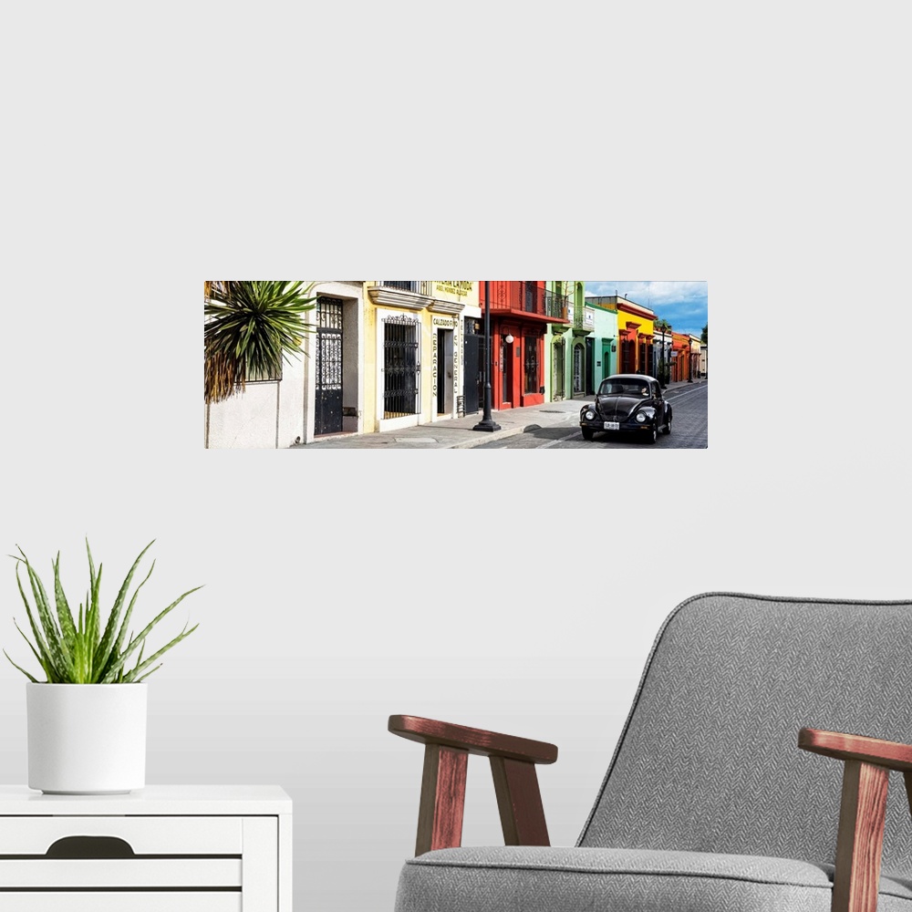 A modern room featuring Panoramic photograph of a classic black Volkswagen Beetle driving up a colorful street in Mexico....