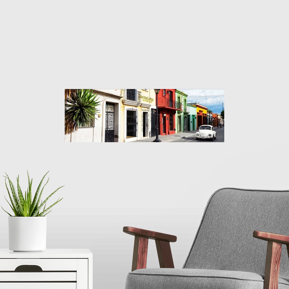 A modern room featuring Panoramic photograph of a classic white Volkswagen Beetle driving up a colorful street in Mexico....