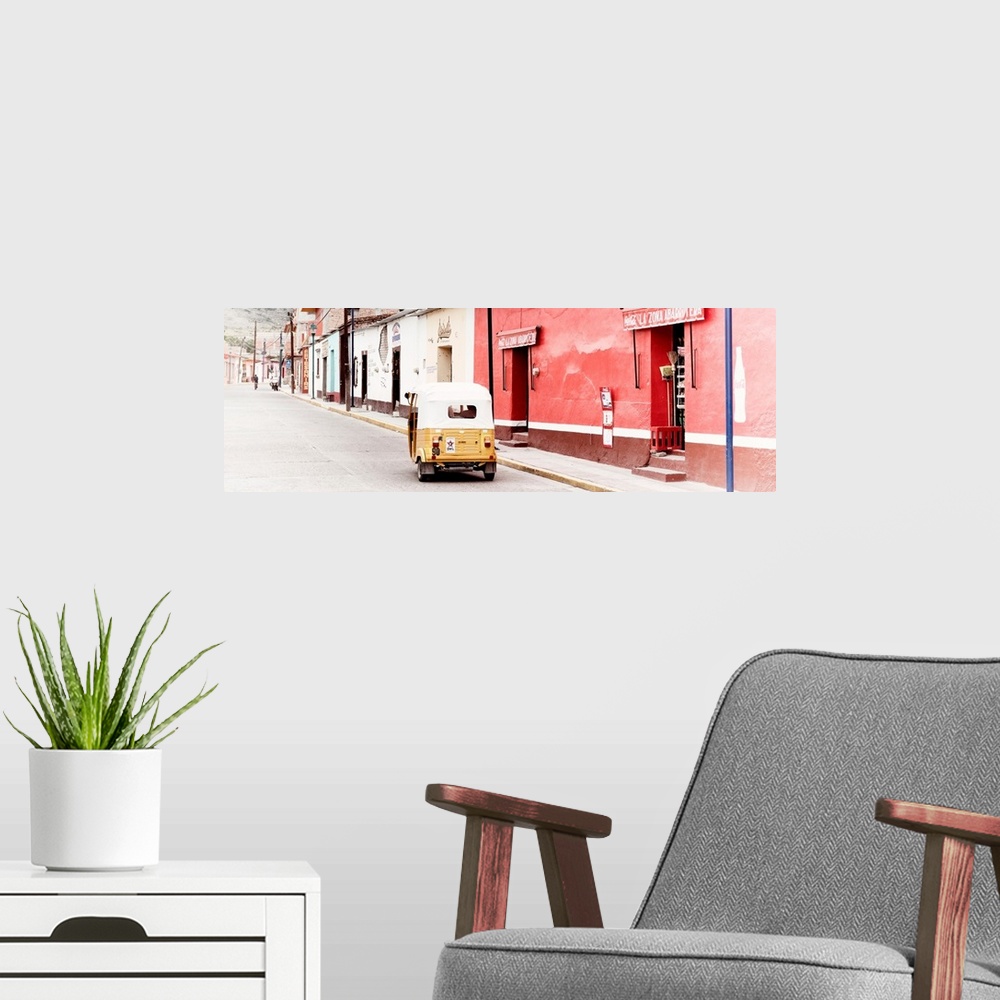 A modern room featuring Panoramic photograph of a street scene in Mexico with a yellow tuck tuk (taxi) driving up the roa...