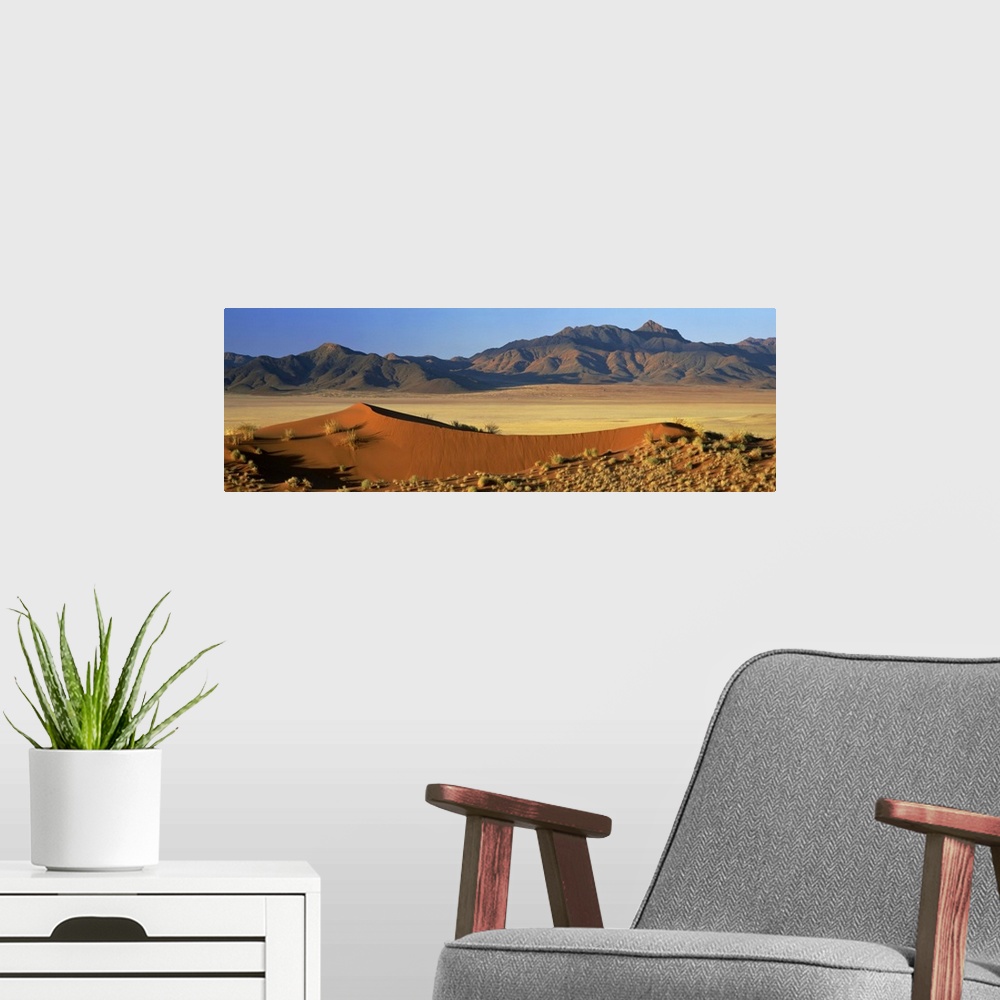 A modern room featuring Panoramic view over orange sand dunes towards mountains, Namibia, Africa