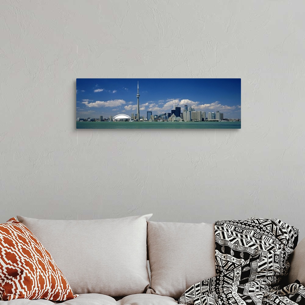 A bohemian room featuring Wide angle photograph on a large canvas of the Ontario skyline, including the CN Tower, in front ...