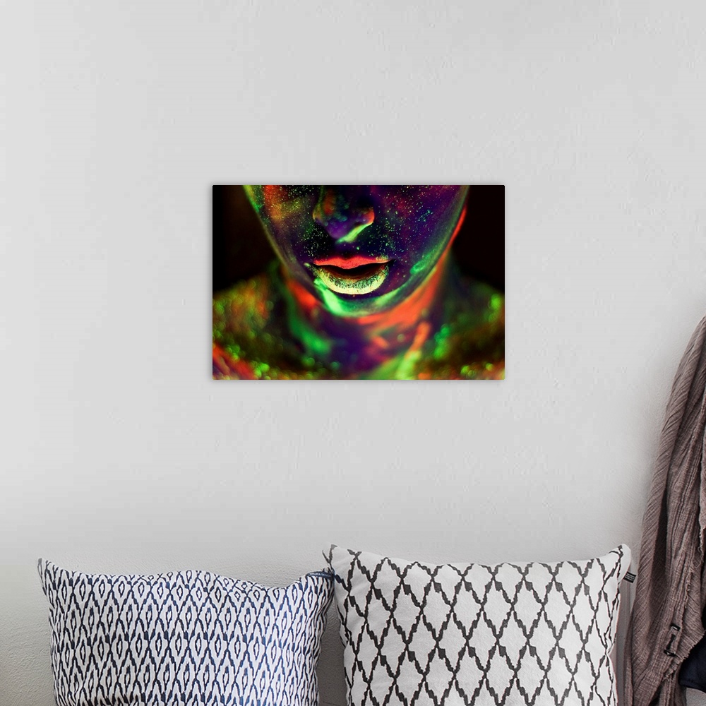 A bohemian room featuring A woman's face and neck covered in glow-in-the-dark paint in neon colors.