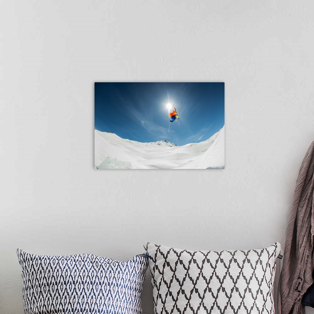 A bohemian room featuring A skier flying through the air over a snowy landscape, Italy.