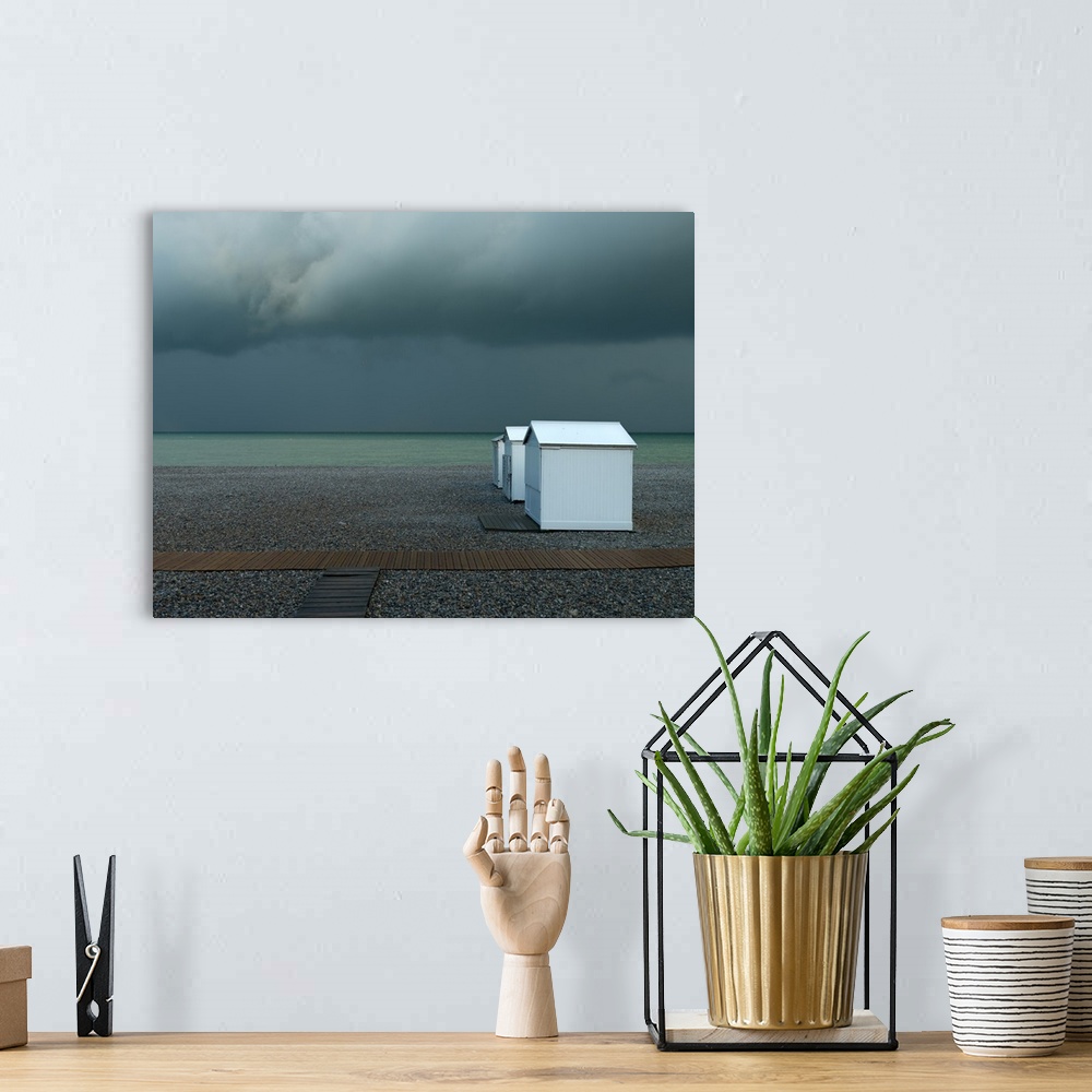 A bohemian room featuring Photograph of a pebble beach shore with a row of white beach cottages on an overcast day.