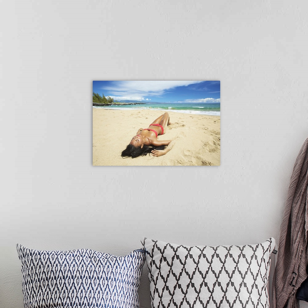 A bohemian room featuring A Young Woman In A Red Bikini Lays On A Sandy Beach; Maui, Hawaii, United States Of America