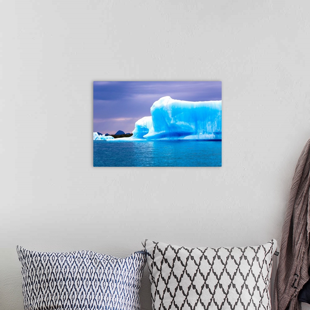 A bohemian room featuring A vibrant blue iceberg floats in Bear Glacier Lagoon in Kenai Fjords National Park on an overcast...
