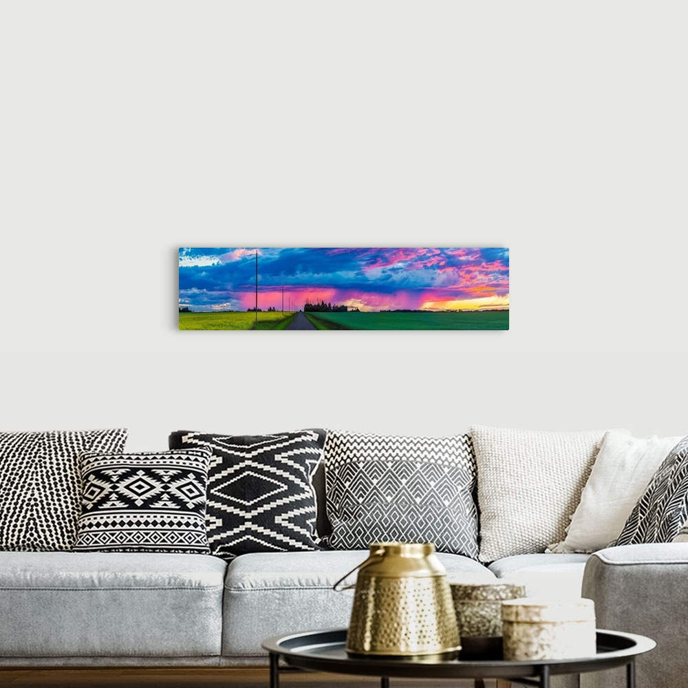 A bohemian room featuring Dramatic colourful sky at sunset over green farmland and a country road; Alberta, Canada