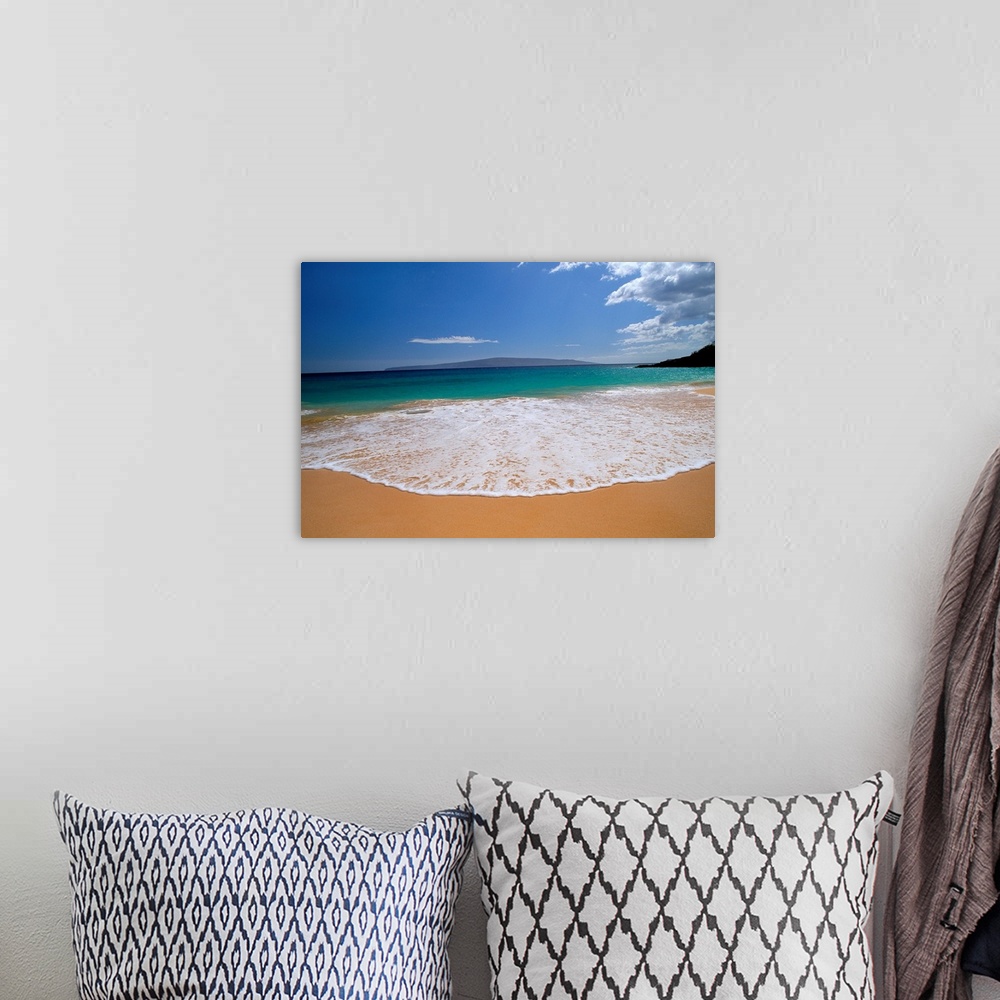 A bohemian room featuring Tide wave rolling up on the sandy beach as a Hawaiian mountain looms in the background.