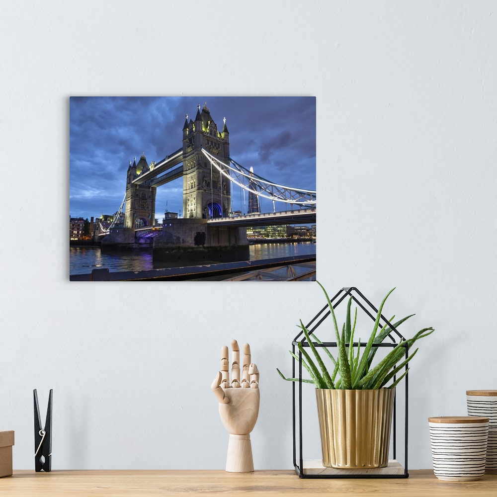 A bohemian room featuring Tower Bridge illuminated at dusk and reflected in the tranquil water of the River Thames; London,...