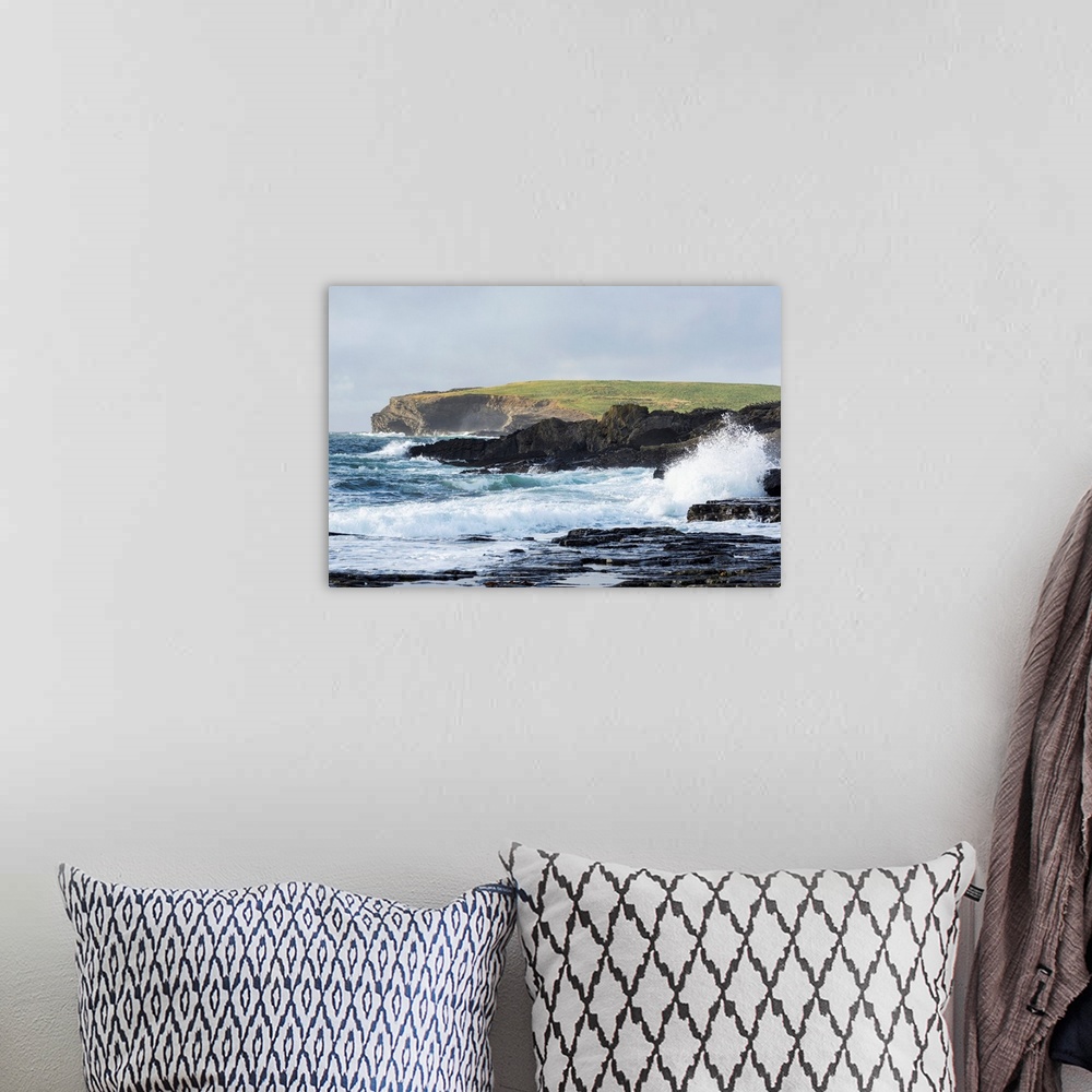 A bohemian room featuring Waves crashing into rocky coast with large grassy hill and cliffs in background, Kilkee, County C...