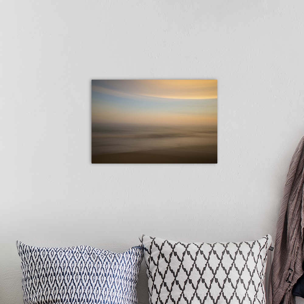 A bohemian room featuring An artistic abstract photograph of a light blue and orange motion blurred cloudscape.