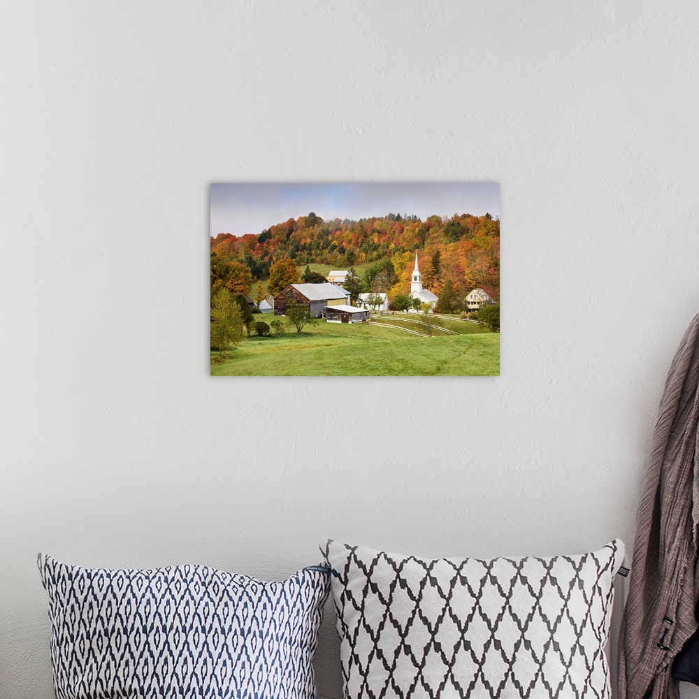A bohemian room featuring Landscape photograph of a hilly village with Fall trees and fog.