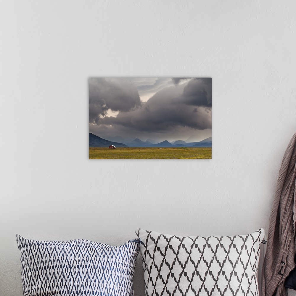 A bohemian room featuring A photograph of a dramatic cloudscape hanging over an Icelandic landscape.