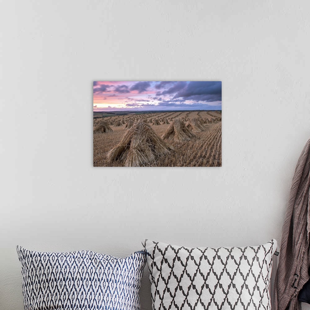A bohemian room featuring Haystacks in a field under a sky with pink and purple sunset light.