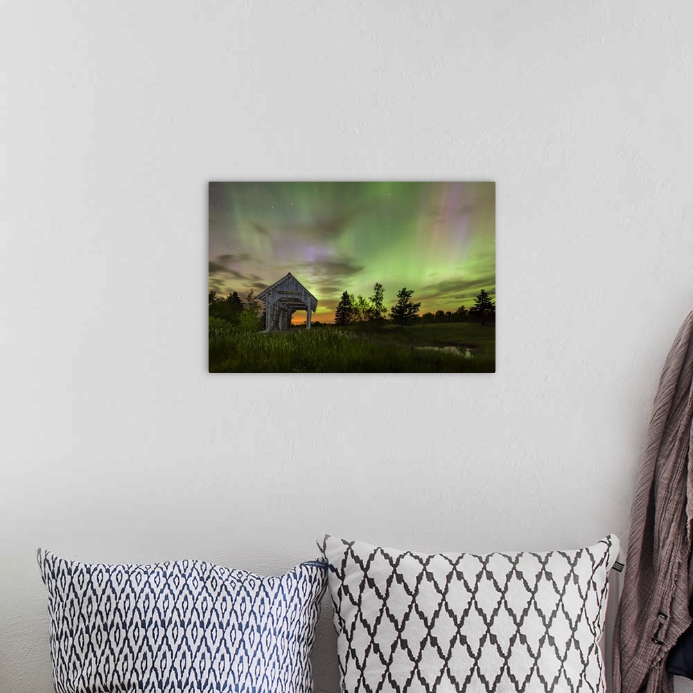 A bohemian room featuring Long exposure photograph of the Northern Lights at night in an open field with a covered bridge.