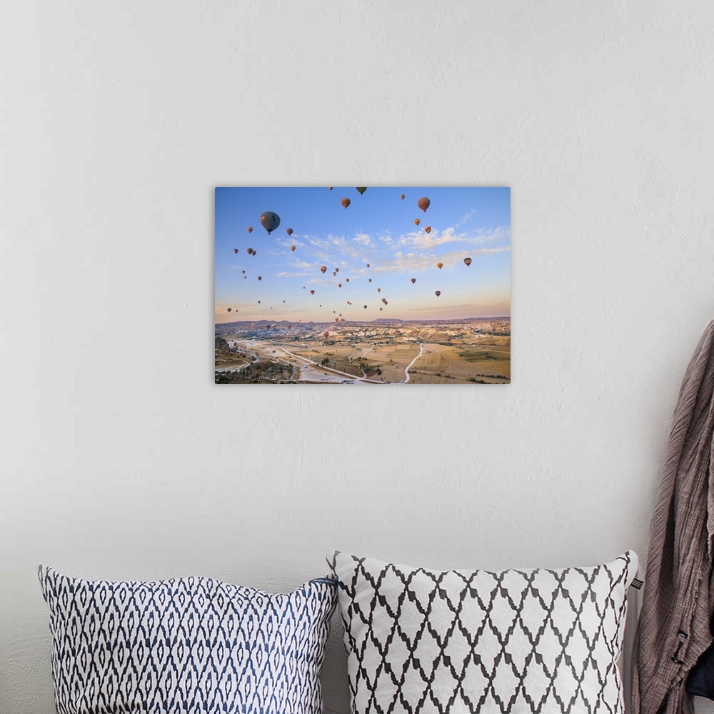 A bohemian room featuring Turkey,Anatolia,Cappadocia, Goreme. Hot air balloons flying above/among rock formations and field...