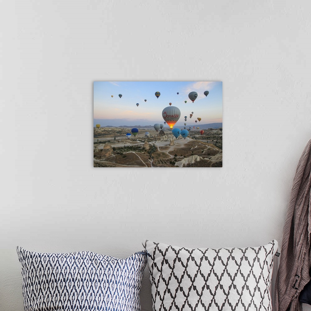 A bohemian room featuring Turkey,Anatolia,Cappadocia, Goreme. Hot air balloons flying above/among rock formations and field...