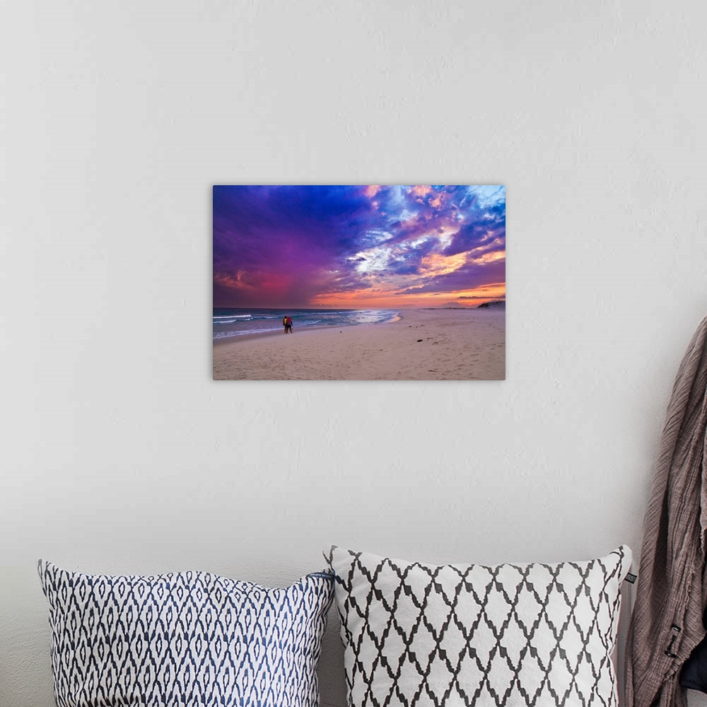 A bohemian room featuring People walking on the beach during a pink and purple sunset along the Gulf Islands National Seash...