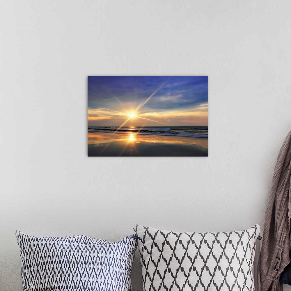 A bohemian room featuring The sunrises over the ocean and reflects on the waves of a sandy beach in this landscape photograph.