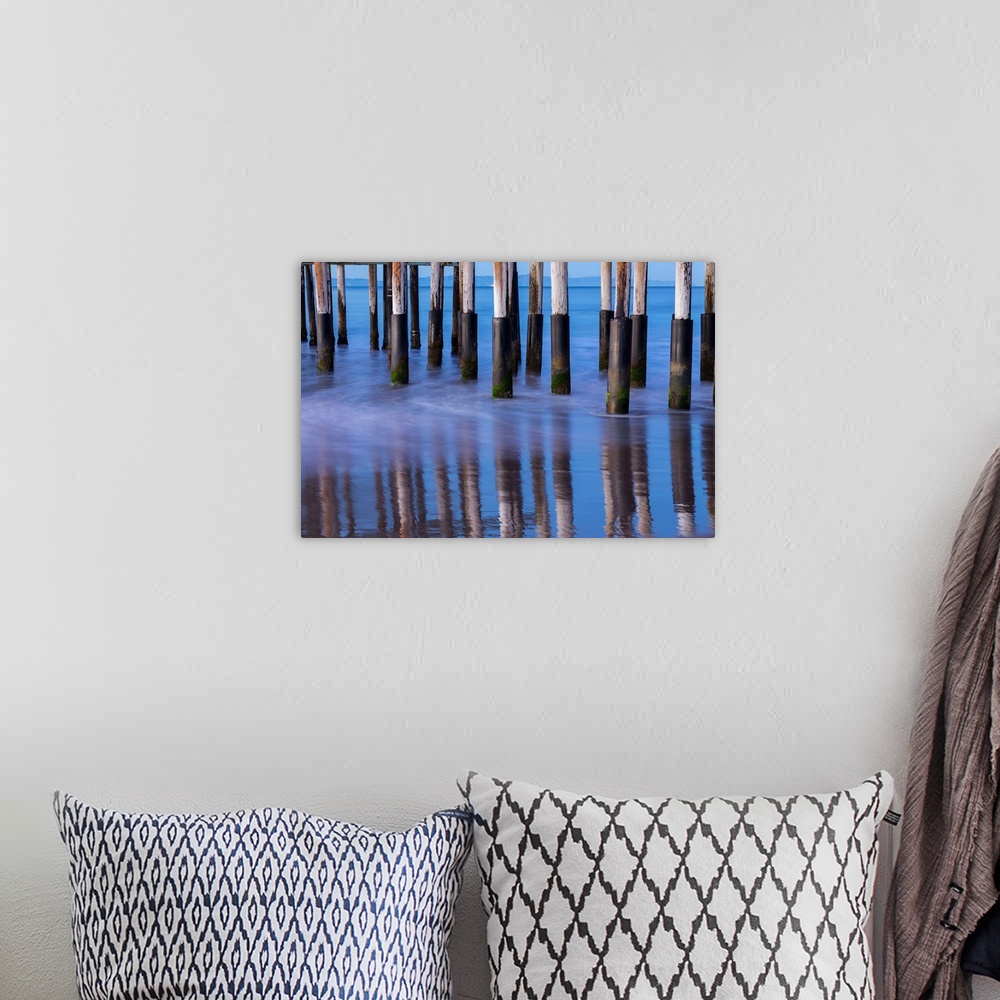 A bohemian room featuring Photograph of the bottom of Ventura Pier pilings reflecting into the ocean water with mountains i...