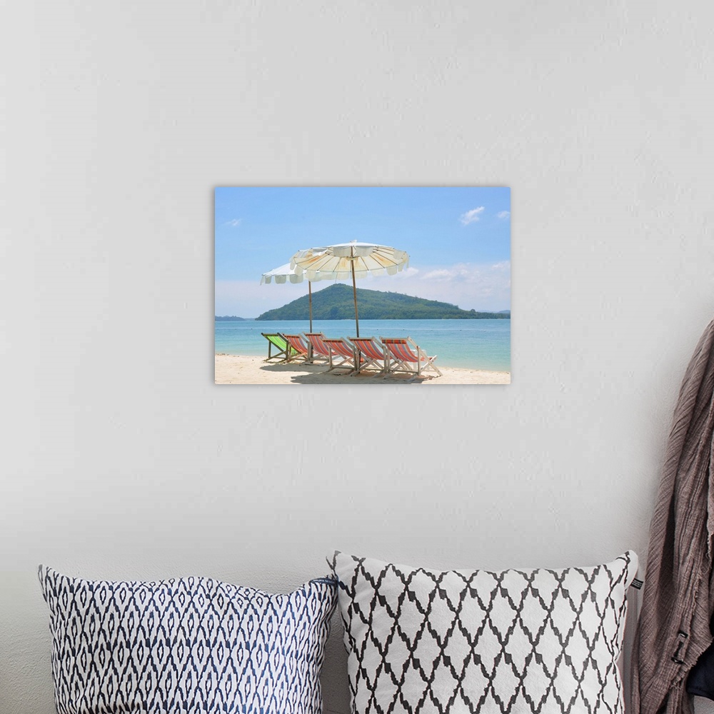 A bohemian room featuring Beach chair and umbrella on beach and Rang Yai Island background.