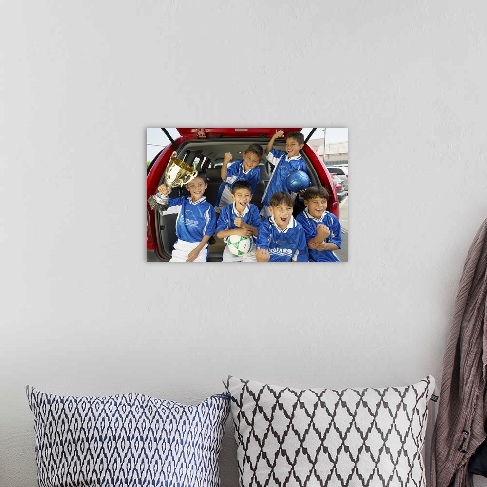 A bohemian room featuring Boys (7-11) football team in car boot, holding trophy, smiling