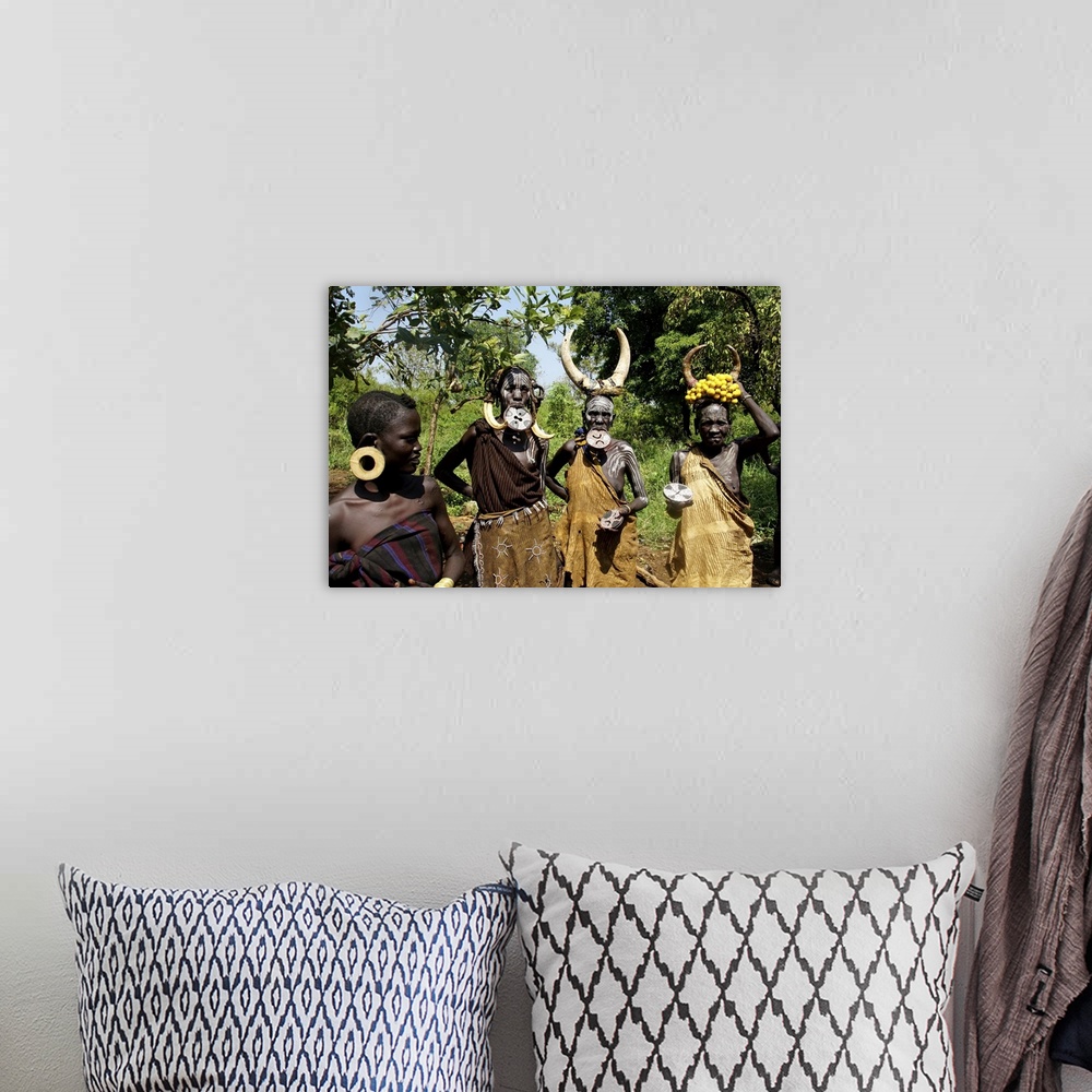 A bohemian room featuring Close up of four traditionally costumed Mursi women. Jinka, Ethiopia, Africa, February 21, 2020.