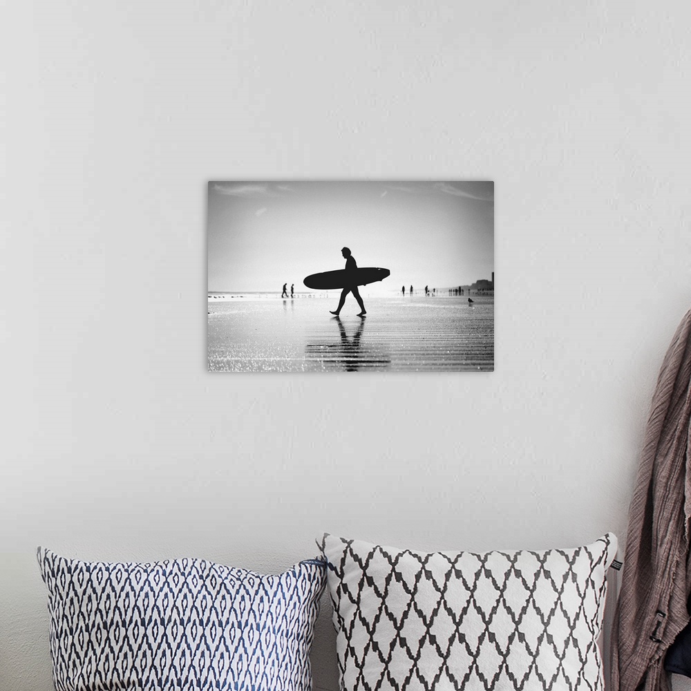 A bohemian room featuring Silhouette of man walking with skateboard on beach.